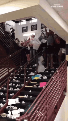People throw an avalanche of papers down a large stairwell